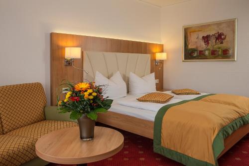a hotel room with a bed and a table with a vase of flowers at Johannesbad Thermalhotel Ludwig Thoma in Bad Füssing