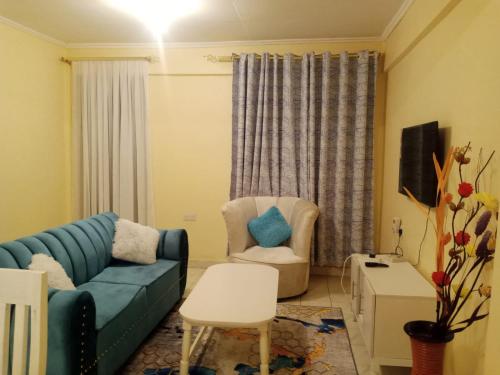 a living room with a blue couch and a chair at Jabali- Zuriel homes 1 bedroom apartment in Kakamega