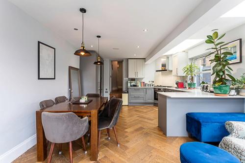 倫敦的住宿－Modern and Spacious Colliers Wood Home，厨房以及带桌子和蓝色沙发的用餐室。