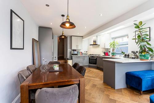倫敦的住宿－Modern and Spacious Colliers Wood Home，厨房以及带桌椅的起居室。