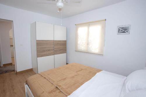 a white bedroom with a bed and a window at Garten und Pool in San Vicente del Raspeig
