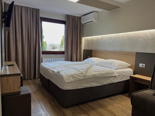 a bedroom with a bed and a window at Hotel Roškar in Ptuj