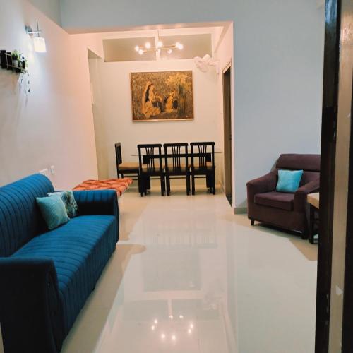 a living room with blue couches and a dining room at NESTER HOMESTAY in Guwahati