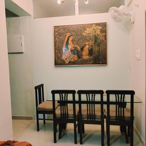a painting hanging on a wall above a table and chairs at NESTER HOMESTAY in Guwahati