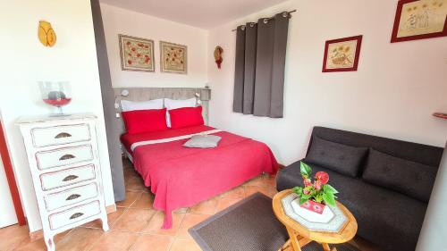 a small bedroom with a red bed and a couch at la cigale sous l'olivier in Le Castellet