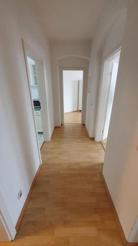 een lege hal met witte muren en een houten vloer bij RB Unterkünfte IV in Maagdenburg