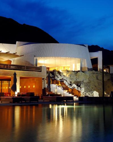 a large building with a rock wall at night at Retac Qunay Dahab Resort & SPA in Dahab