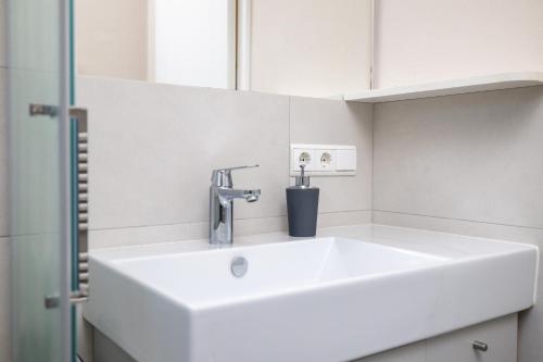 La salle de bains est pourvue d'un lavabo blanc et d'un miroir. dans l'établissement Apartment Bellevue Seis, à Alpe di Siusi