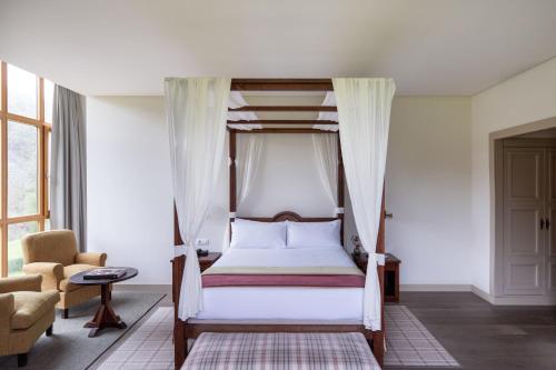 a bedroom with a canopy bed and a chair at Parador de Cangas de Onís in Villanueva de Cangas de Onís