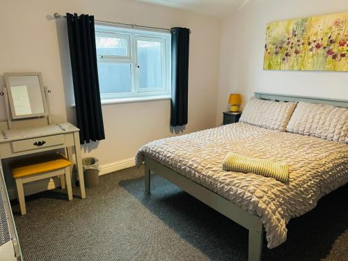 a bedroom with a bed and a desk and a window at The Garden Room in Filey