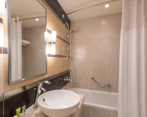 Hurghada Long Beach Resort في الغردقة: حمام مع حوض ومرآة وحوض استحمام