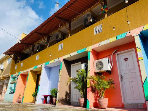 um edifício colorido com plantas em frente em Pousada Maria Bonita Abreu e Lima em Maricota