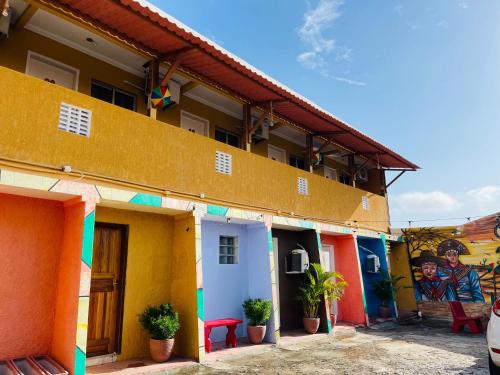 una fila de casas coloridas con un mural en Pousada Maria Bonita Abreu e Lima en Maricota