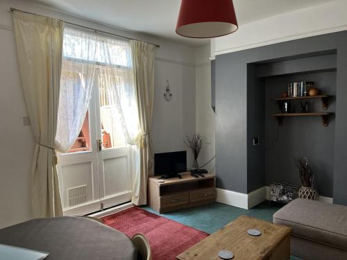 a living room with a couch and a tv and a window at Broadstairs Terrace: Central Broadstairs Flat in Broadstairs