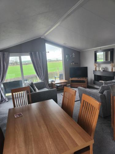 een woonkamer met een houten tafel en stoelen bij Hesket caravan park Plot Number 7 STRICTLY NOT FOR COMMERCIAL USE in High Hesket