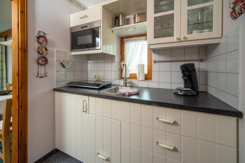 a kitchen with white cabinets and a black counter top at Landhaus Charivari Sommer-Hörnerbahnen kostenlos in Bolsterlang