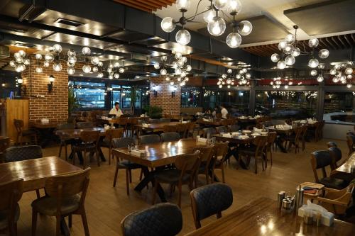 a restaurant with wooden tables and chairs and chandeliers at Mihman Hotel in Tuzla