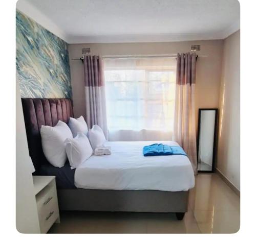 a bedroom with a large bed with a window at Emerald Suite 3-Bed House in Harare in Harare