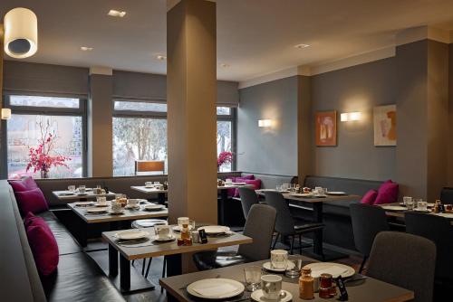 un comedor con mesas, sillas y ventanas en Hotel St. Annen, en Hamburgo