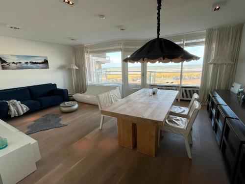 uma sala de estar com uma mesa e um sofá azul em Sterflat 97 em Egmond aan Zee
