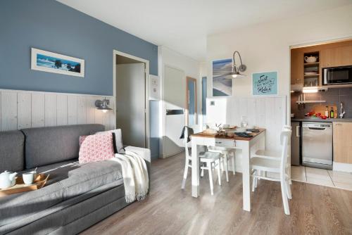 a living room with a couch and a table and a kitchen at Résidence Pierre & Vacances Premium Le Domaine de Cramphore in Le Pouliguen