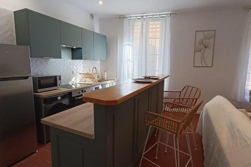 a kitchen with a counter and two chairs in it at hypercentre, appartement coquet en rez-de-chaussée in Perpignan