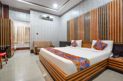 a bedroom with a large bed and a chair at FabHotel Rahul Palace in Nagpur