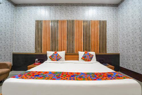 a bedroom with a large white bed with colorful pillows at FabHotel Rahul Palace in Nagpur