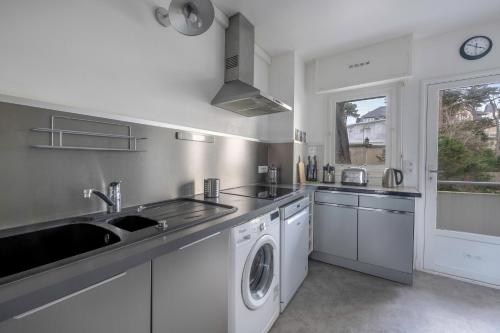 une cuisine avec un évier et une machine à laver dans l'établissement Séjour à 4 - Les pied dans l'eau - Vue mer, à La Baule