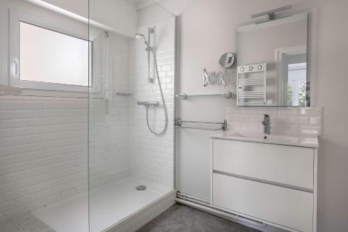 une salle de bain blanche avec une douche et un lavabo dans l'établissement Séjour à 4 - Les pied dans l'eau - Vue mer, à La Baule