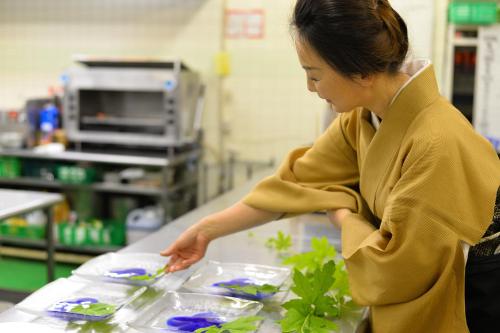 a woman preparing food on a counter in a store at Kotonoyado Musashino in Nara