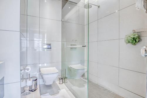 a white bathroom with a toilet and a shower at Luxurious One Bedroom Apartment In Sandton in Johannesburg
