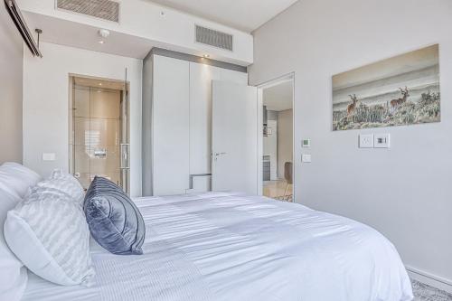 a white bedroom with a large white bed with pillows at Luxurious One Bedroom Apartment In Sandton in Johannesburg