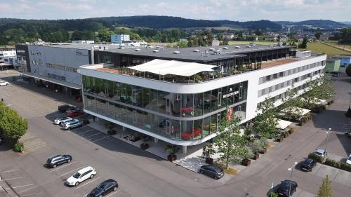 a large white building with a parking lot with cars at Hotel Meilenstein in Langenthal