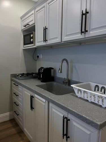 een keuken met witte kasten en een spoelbak bij بيت عطلات مفروش بالخبر in Al Khobar
