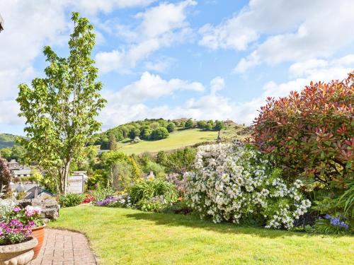 a garden with flowers and a hill in the background at Hill Crest Country Guest House in Newby Bridge