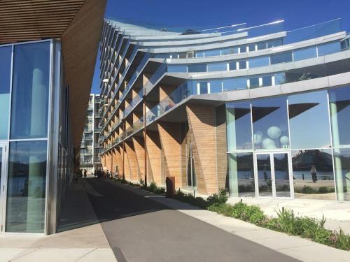 a large building with glass windows next to a street at Beach house apartment in New York style in Aarhus