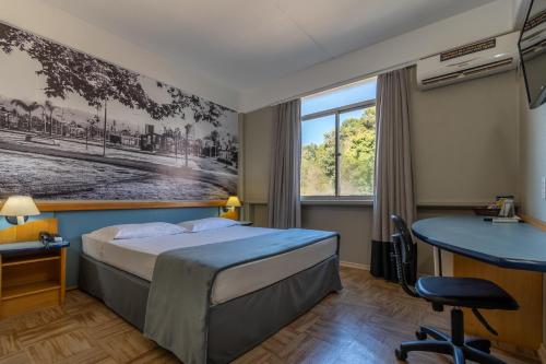 CaçadorにあるBrivali Hotel Centroのベッドとデスクが備わるホテルルームです。