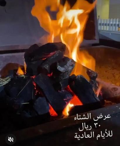 a fire in a grill with flames in the background at شاليه ليالي السيب in Seeb