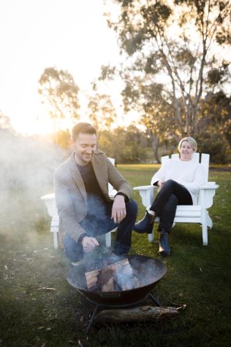 a man and woman sitting on a bench next to a fire at Goldfield Glamping in Clydesdale