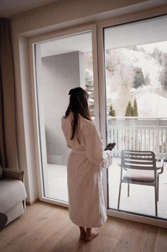 a woman in a white dress looking out of a window at Anett hotel in Vipiteno