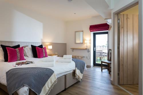 a bedroom with a large white bed with pink pillows at The Barn at Plas Ashpool Sleeps 8 in Llandyrnog