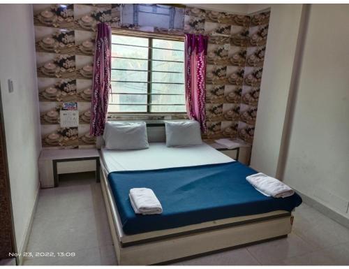 a small bedroom with a bed in a room with a window at Hotel Shiv Sadan, Somnath in Somnath