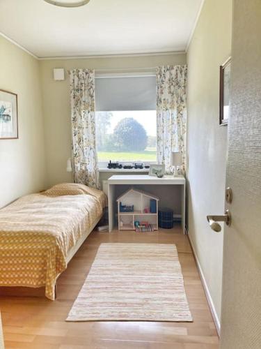 a bedroom with a bed and a desk and a window at Country house with sea view near Hovs Hallar in Båstad