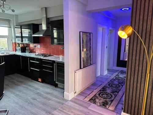 een keuken met paarse muren, zwarte kasten en een tapijt bij Luxury 9ine Lush Jacuzzi Apartment with Balcony in Birmingham