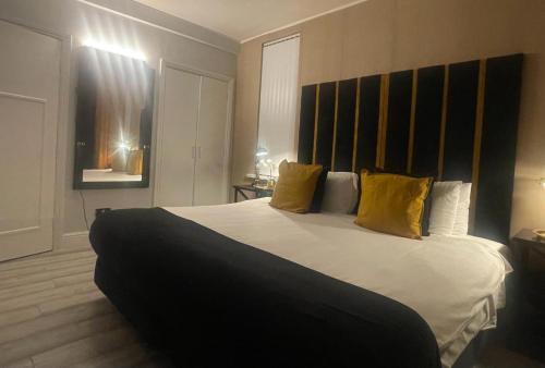 een slaapkamer met een groot wit bed met gele kussens bij Luxury 9ine Lush Jacuzzi Apartment with Balcony in Birmingham