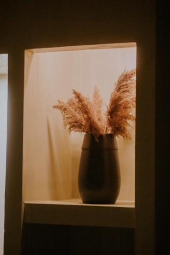 a black vase sitting on a shelf with a plant at Dim's Hotel & Restaurant in Korçë