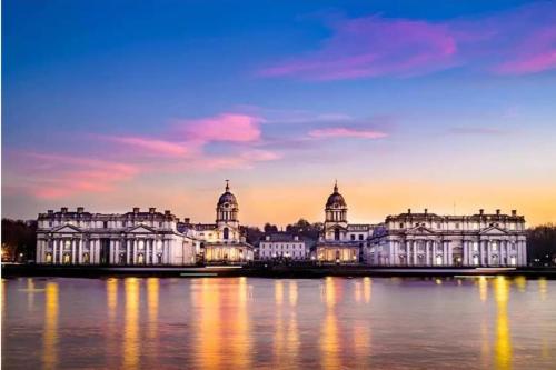 a view of a large building on the water at sunset at Greenwich Haven, London in London
