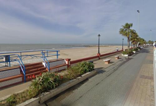 a beach with benches and palm trees and the ocean at MAGNIFICO PISO JUNTO A PLAYA DE REGLA in Chipiona