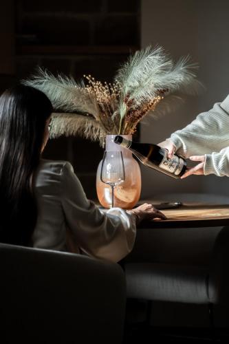a woman sitting at a table with a bottle of wine at Sella&Mosca Casa Villamarina in Alghero